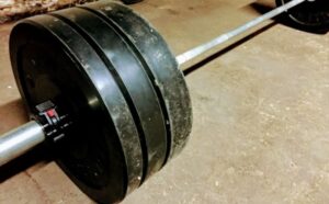 Barbell and plates on garage gym floor ready for a deadlift