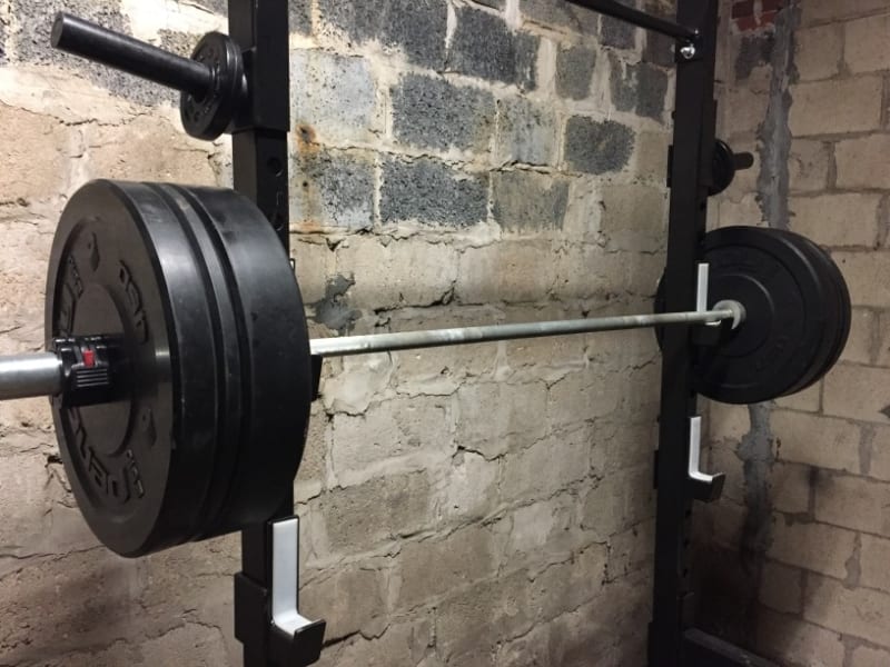 Barbell on a squat rack in a garage gym
